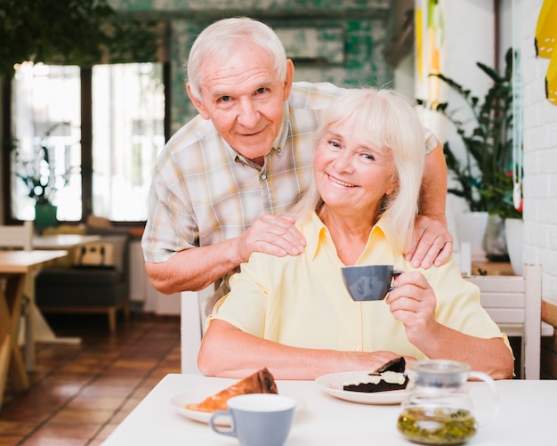 Sonriente pareja senior sentado en la cafetería con tazas de té