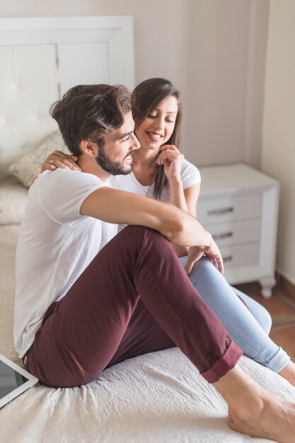 Sonriente pareja sentada en la cama