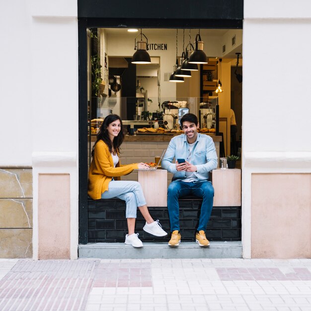Sonriente pareja sentada en la zona de la cafetería abierta