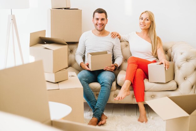 Sonriente pareja en el sofá con cajas