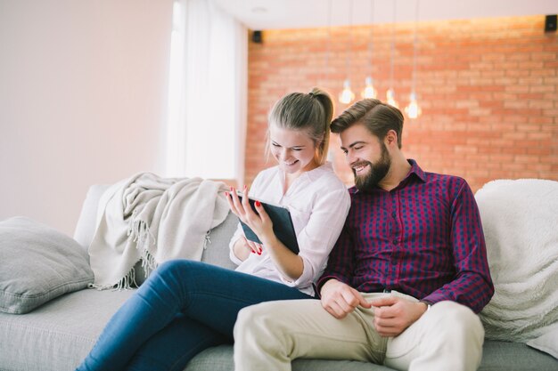 Sonriente pareja con tableta en casa