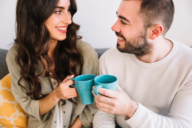 Sonriente pareja con tazas en casa