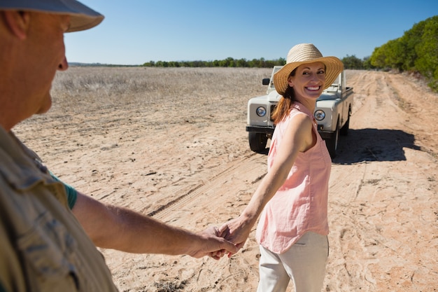 Sonriente pareja tomados de la mano en el paisaje