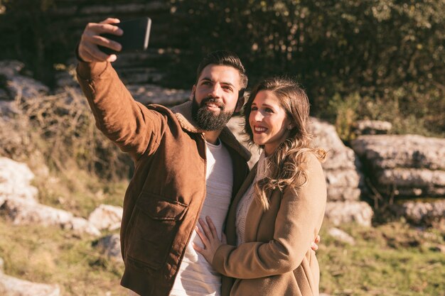 Sonriente pareja tomando un selfie en la naturaleza