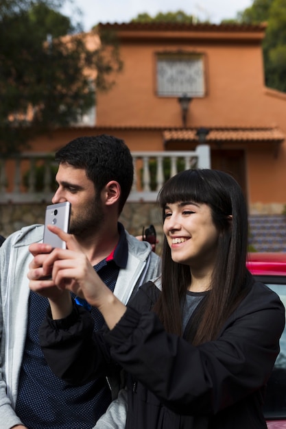 Foto gratuita sonriente pareja tomando selfie con teléfono con cámara