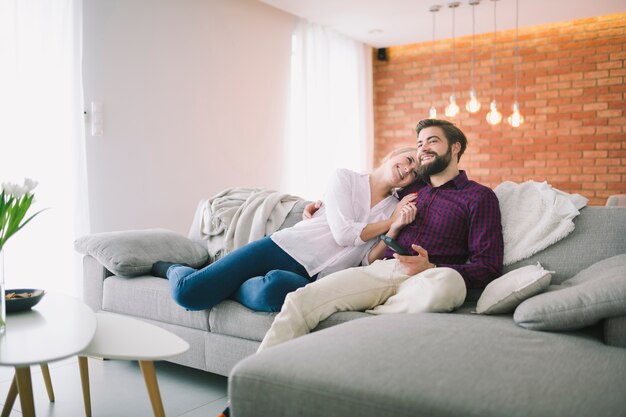 Sonriente pareja viendo la televisión en casa