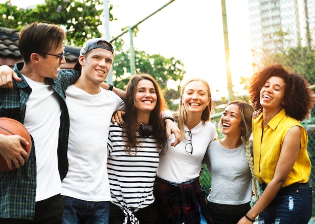 Sonrientes amigos adultos jóvenes felices brazos alrededor del hombro al aire libre amistad y concepto de conexión