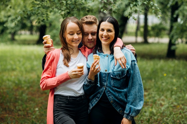 Sonrientes amigos pasando el rato en el parque con helado