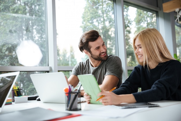 Sonrientes colegas jóvenes sentados en coworking de oficina