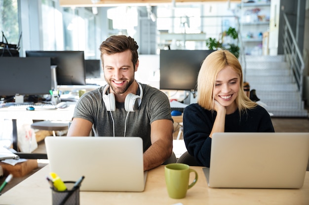 Sonrientes colegas jóvenes sentados en coworking de oficina