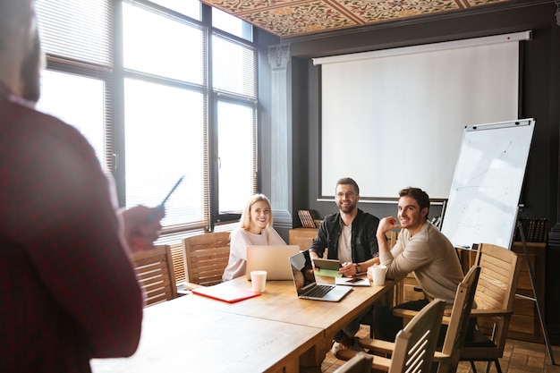 Sonrientes colegas que trabajan con computadoras portátiles y portátiles