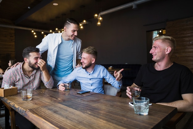 Sonrientes jóvenes amigos disfrutando en el restaurante