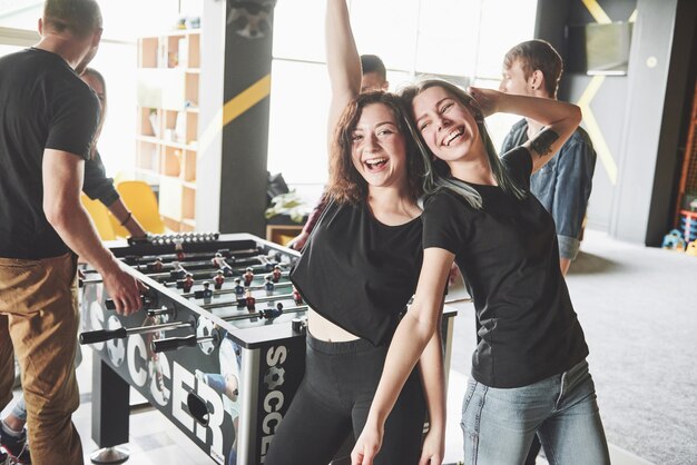 Sonrientes jóvenes jugando futbolín mientras están en el interior