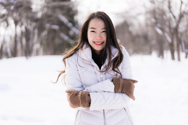 Sonrisa asiática joven hermosa de la mujer feliz para el viaje en la estación del invierno de la nieve