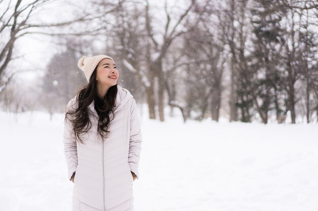 Sonrisa asiática joven hermosa de la mujer feliz para el viaje en la estación del invierno de la nieve