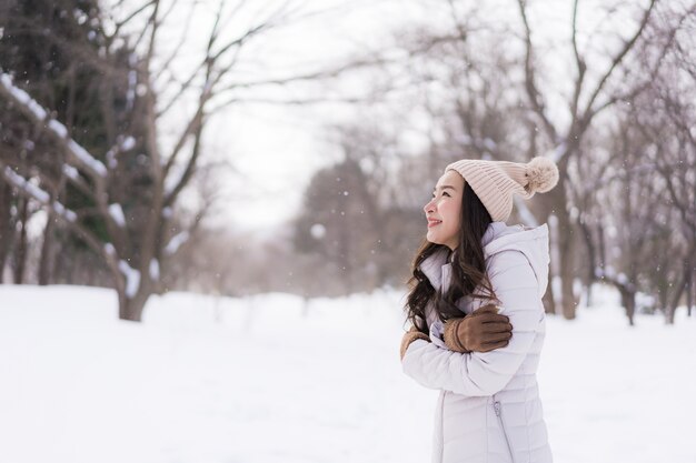 Sonrisa asiática joven hermosa de la mujer feliz para el viaje en la estación del invierno de la nieve