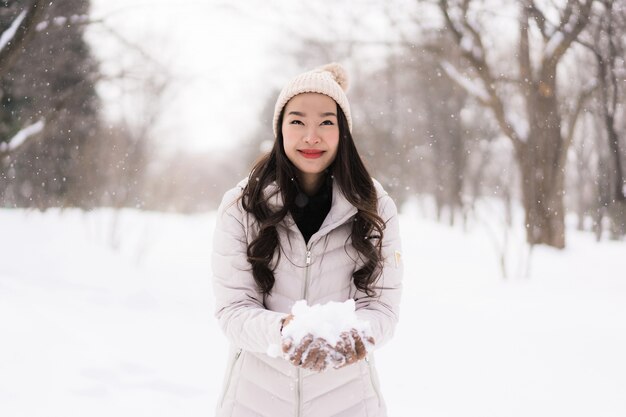 Sonrisa asiática joven hermosa de la mujer feliz para el viaje en la estación del invierno de la nieve