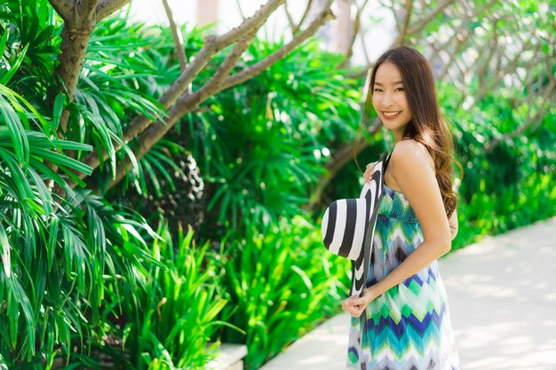 Sonrisa asiática joven hermosa de la mujer del retrato y feliz alrededor del jardín al aire libre