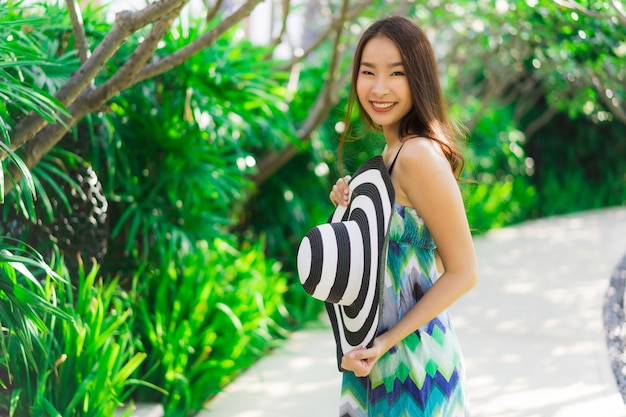 Sonrisa asiática joven hermosa de la mujer del retrato y feliz alrededor del jardín al aire libre