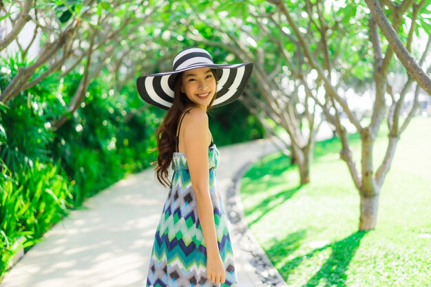 Sonrisa asiática joven hermosa de la mujer del retrato y feliz alrededor del jardín al aire libre