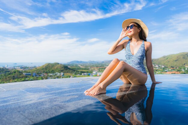 La sonrisa asiática joven hermosa de la mujer del retrato feliz se relaja alrededor de piscina en el centro turístico del hotel para el ocio