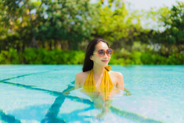 La sonrisa asiática joven hermosa de la mujer del retrato feliz se relaja y el ocio en la piscina