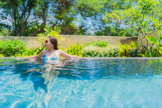 La sonrisa asiática joven hermosa de la mujer del retrato feliz se relaja y el ocio en la piscina