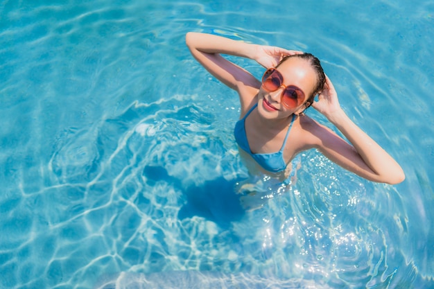 La sonrisa asiática joven hermosa de la mujer del retrato feliz se relaja y el ocio en la piscina