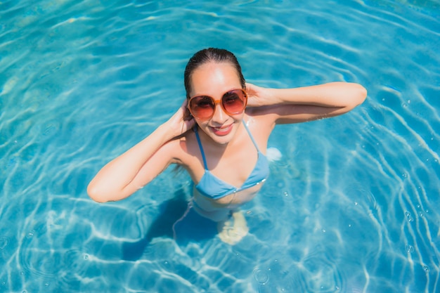 La sonrisa asiática joven hermosa de la mujer del retrato feliz se relaja y el ocio en la piscina