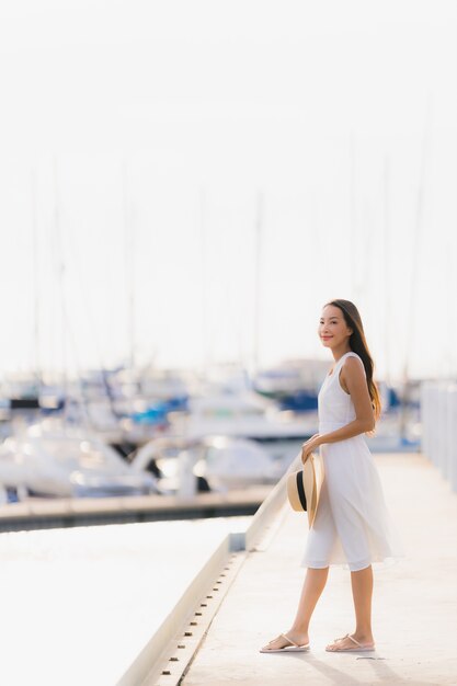 La sonrisa asiática joven hermosa del ocio de la mujer del retrato feliz se relaja alrededor de puerto del yate