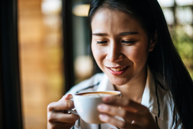 La sonrisa asiática de la mujer del retrato se relaja en café de la cafetería