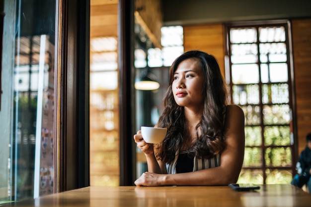 La sonrisa asiática de la mujer del retrato se relaja en café de la cafetería