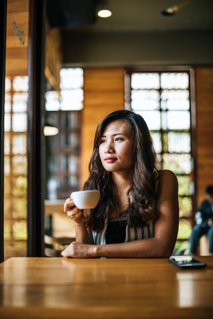 La sonrisa asiática de la mujer del retrato se relaja en café de la cafetería