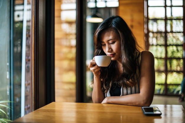 La sonrisa asiática de la mujer del retrato se relaja en café de la cafetería