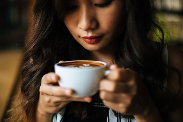 La sonrisa asiática de la mujer del retrato se relaja en café de la cafetería