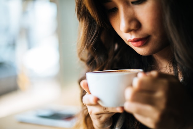 La sonrisa asiática de la mujer del retrato se relaja en café de la cafetería