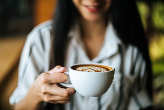 La sonrisa asiática de la mujer del retrato se relaja en café de la cafetería