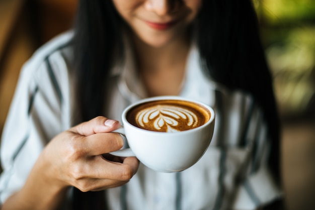 La sonrisa asiática de la mujer del retrato se relaja en café de la cafetería