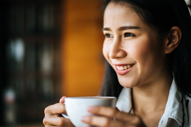 La sonrisa asiática de la mujer del retrato se relaja en café de la cafetería