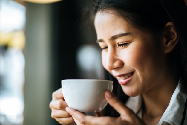 La sonrisa asiática de la mujer del retrato se relaja en café de la cafetería