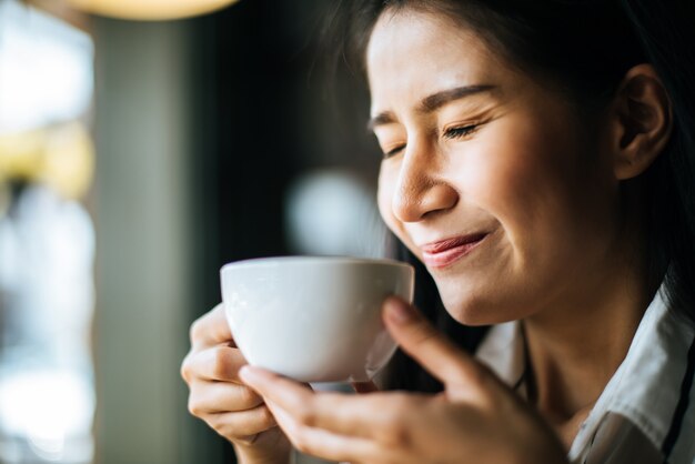 La sonrisa asiática de la mujer del retrato se relaja en café de la cafetería