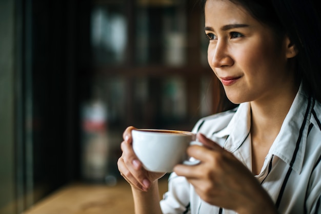 La sonrisa asiática de la mujer del retrato se relaja en café de la cafetería