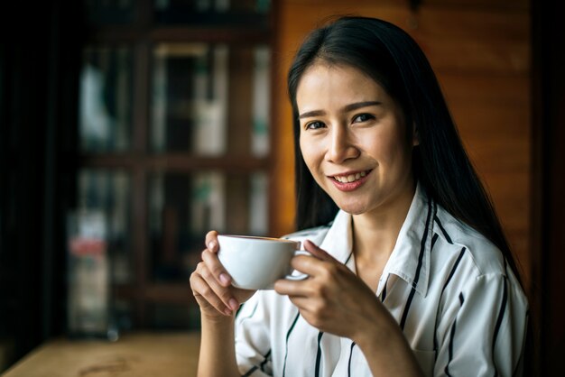 La sonrisa asiática de la mujer del retrato se relaja en café de la cafetería