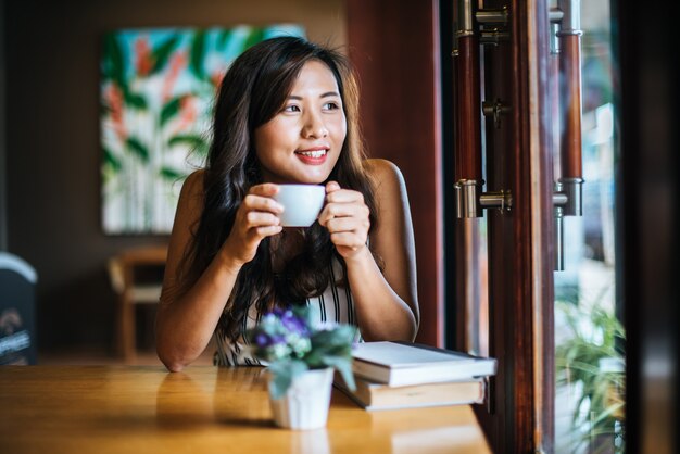 La sonrisa asiática de la mujer del retrato se relaja en café de la cafetería