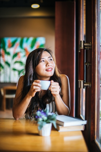 La sonrisa asiática de la mujer del retrato se relaja en café de la cafetería