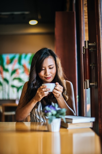 La sonrisa asiática de la mujer del retrato se relaja en café de la cafetería
