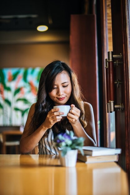 La sonrisa asiática de la mujer del retrato se relaja en café de la cafetería