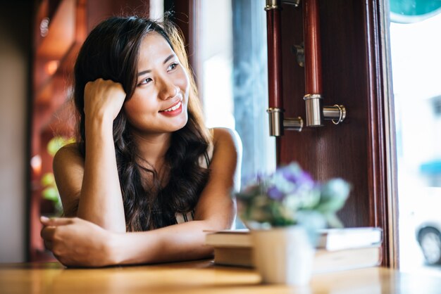 La sonrisa asiática de la mujer del retrato se relaja en café de la cafetería