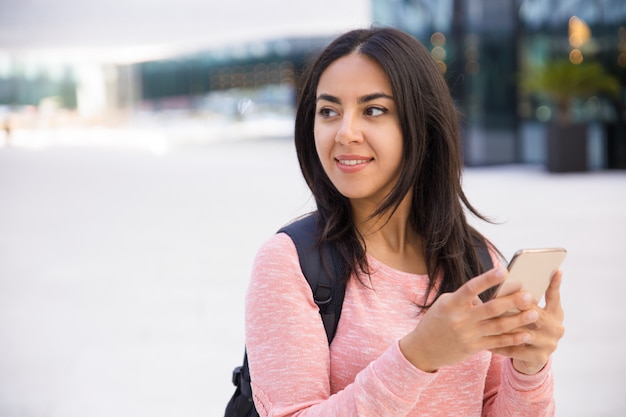 Sonrisa atractiva joven mensajes de texto SMS en el teléfono