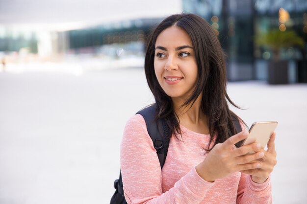 Sonrisa atractiva joven mensajes de texto SMS en el teléfono